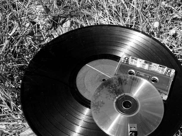 Vinyl record player, cassette tape, CD on grass.