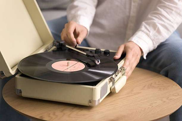 Man placing a record on a portable vinyl record player.
